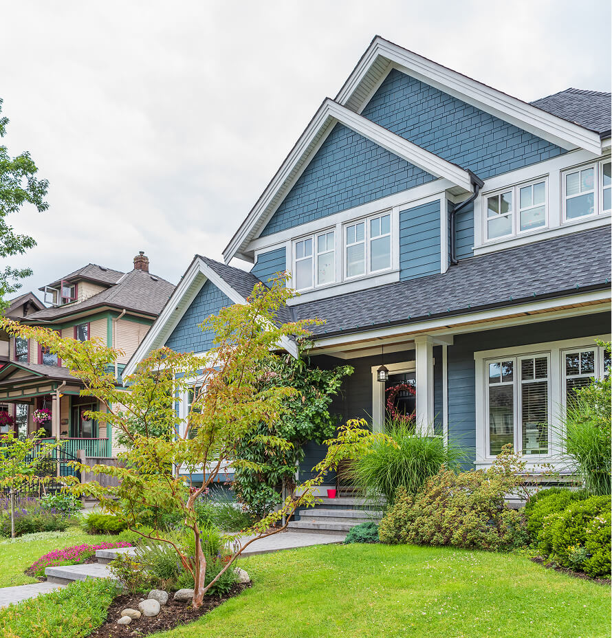 Two-story blue house with a gabled roof and a well-maintained front garden.