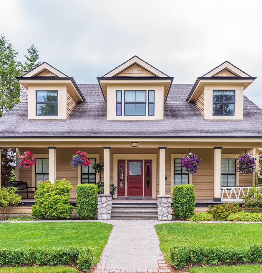 Two-story residential home featuring a front porch, flower baskets, and landscaped yard.