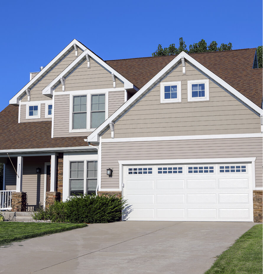Two-story residential home with beige siding and a white garage door.